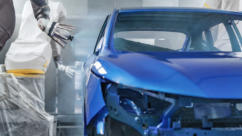 Roboterarm lackiert die Karosserie eines blauen Autos Roboterarm lackiert die Karosserie eines blauen Autos